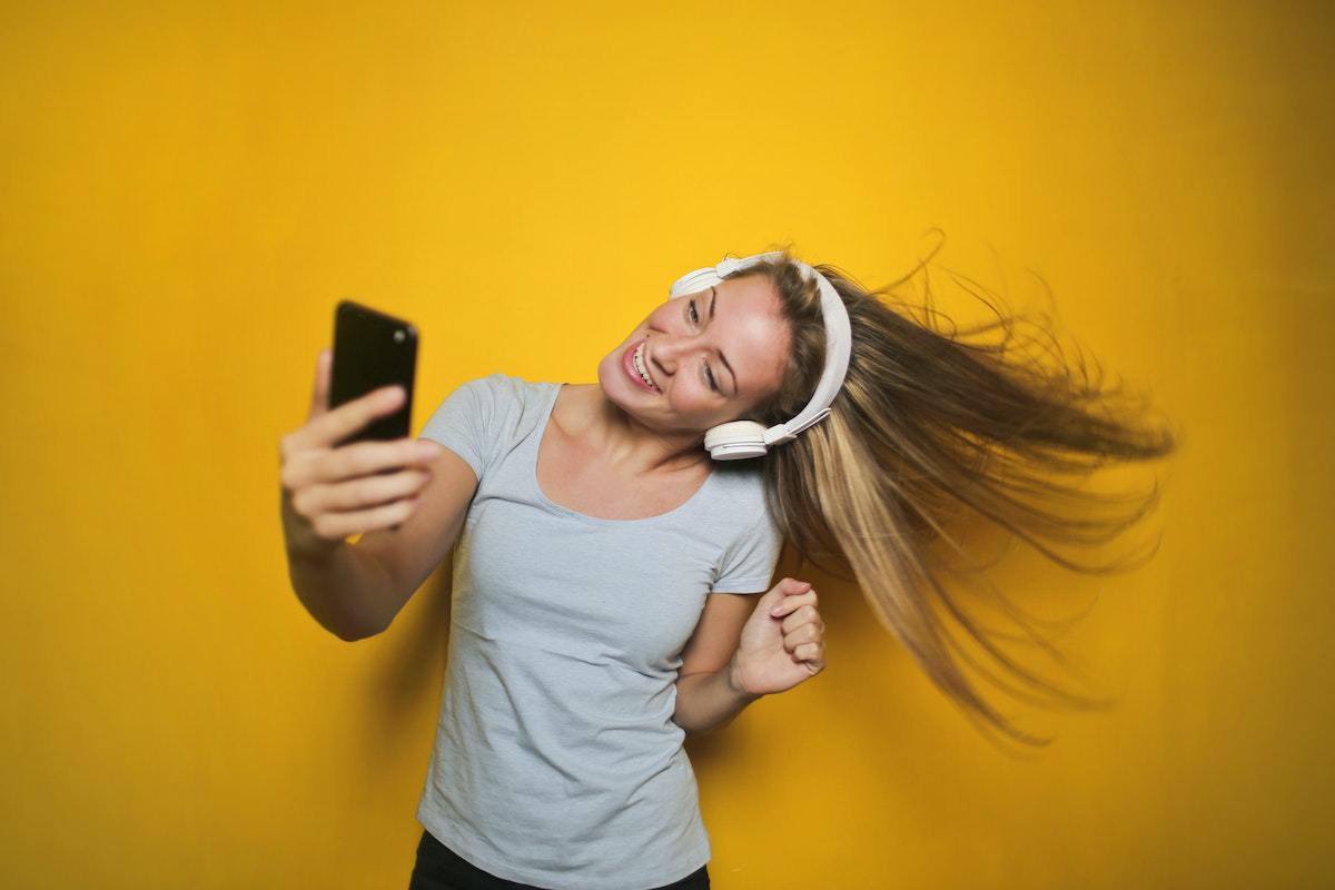 Mulher com celular na mão e fone headset usando Aplicativos de música