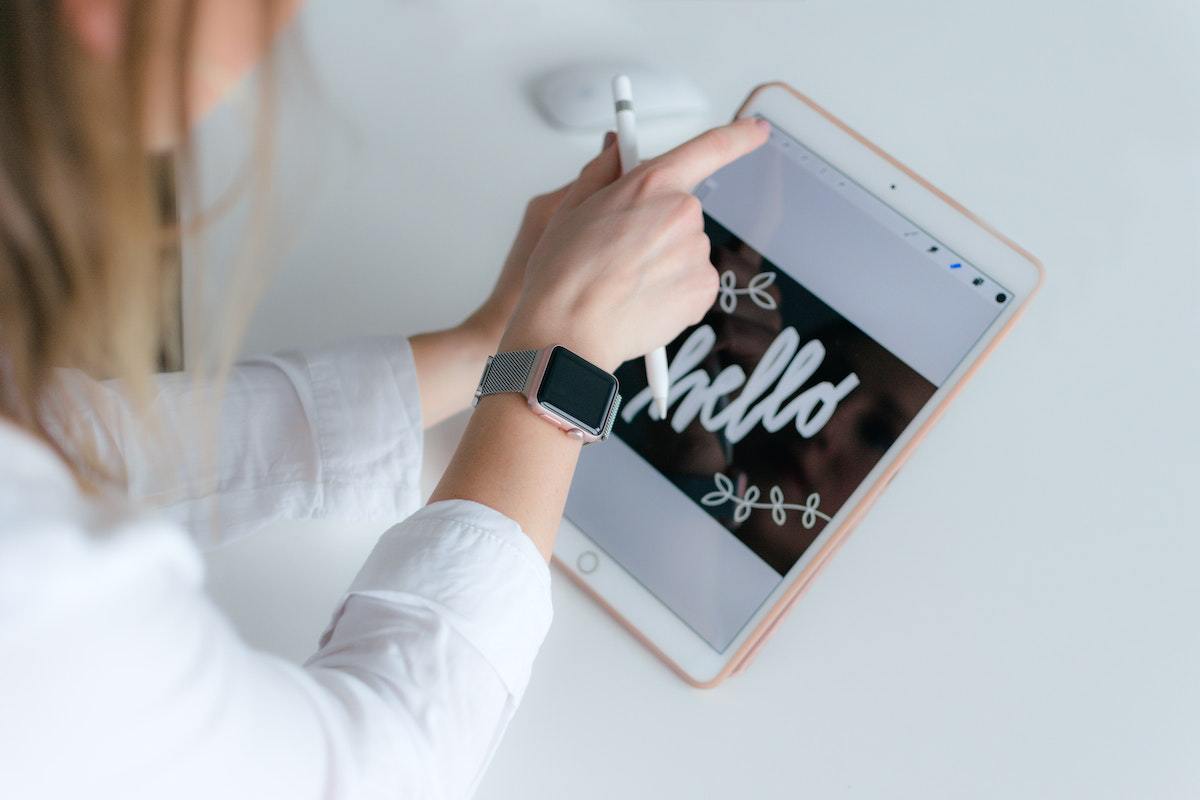 Imagens: Aplicativos pagos Mulher usando Aplicativos pagos em tablet com relógio digital no pulso visualizando imagens com montagem e nome Hello
