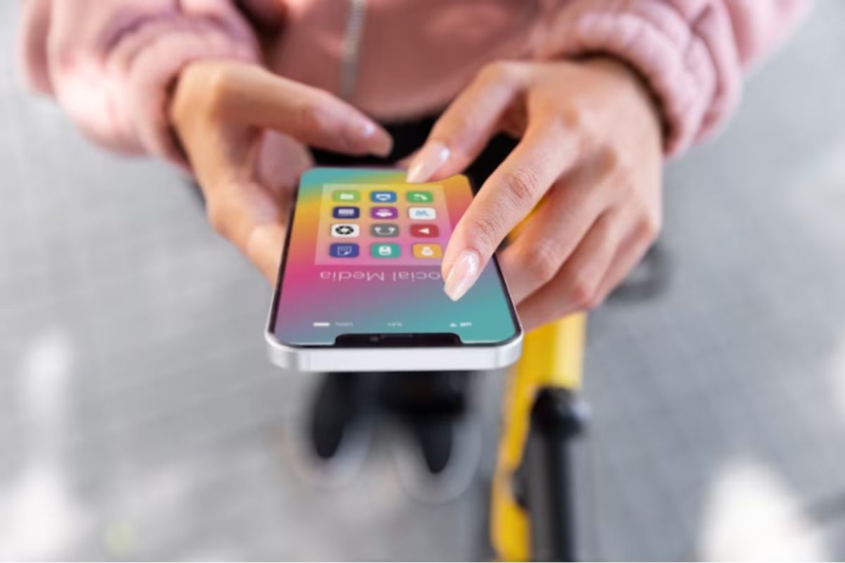 Smartphone: Aplicativos para baixar música Pessoa com smartphone nas mãos com pasta aberta de nome Social Media e Aplicativos para baixar música na mesma