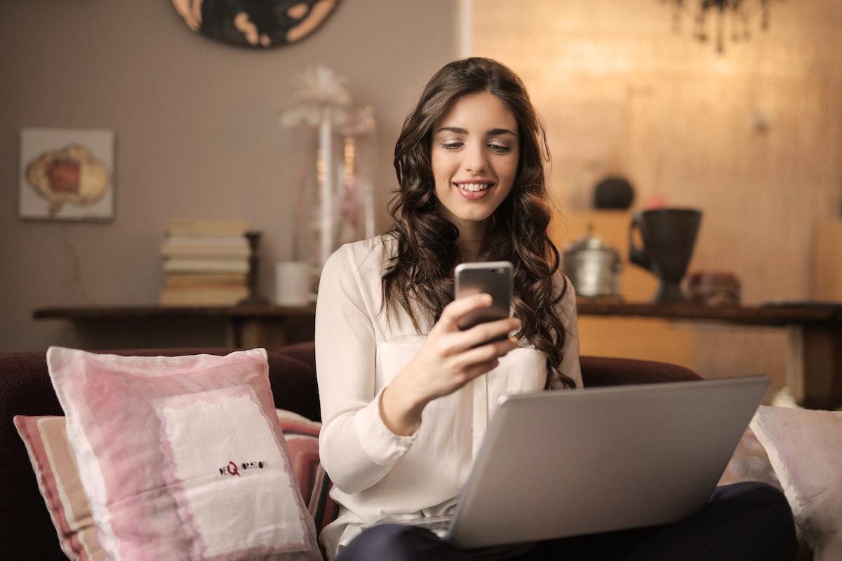 Celular: Apps que pagam por cadastro Apps que pagam por cadastro em celular e notebook usados por mulher em casa