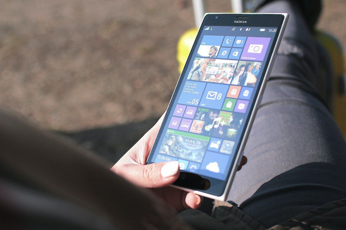 Pessoa usando smartphone Nokia com mão esquerda no seu menu de aplicativos Microsoft