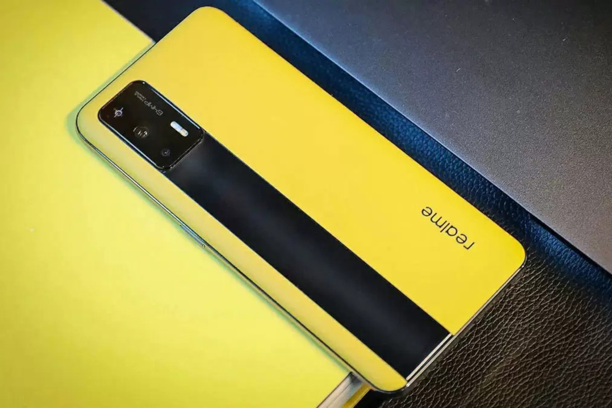 Realme GT amarelo com tela para baixo em cima de superfície de mesma cor