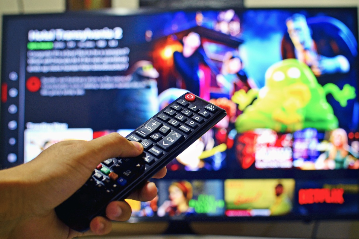 Televisão: Aplicativos TV Aplicativos TV com pessoa usando controle remoto para escolher título na televisão