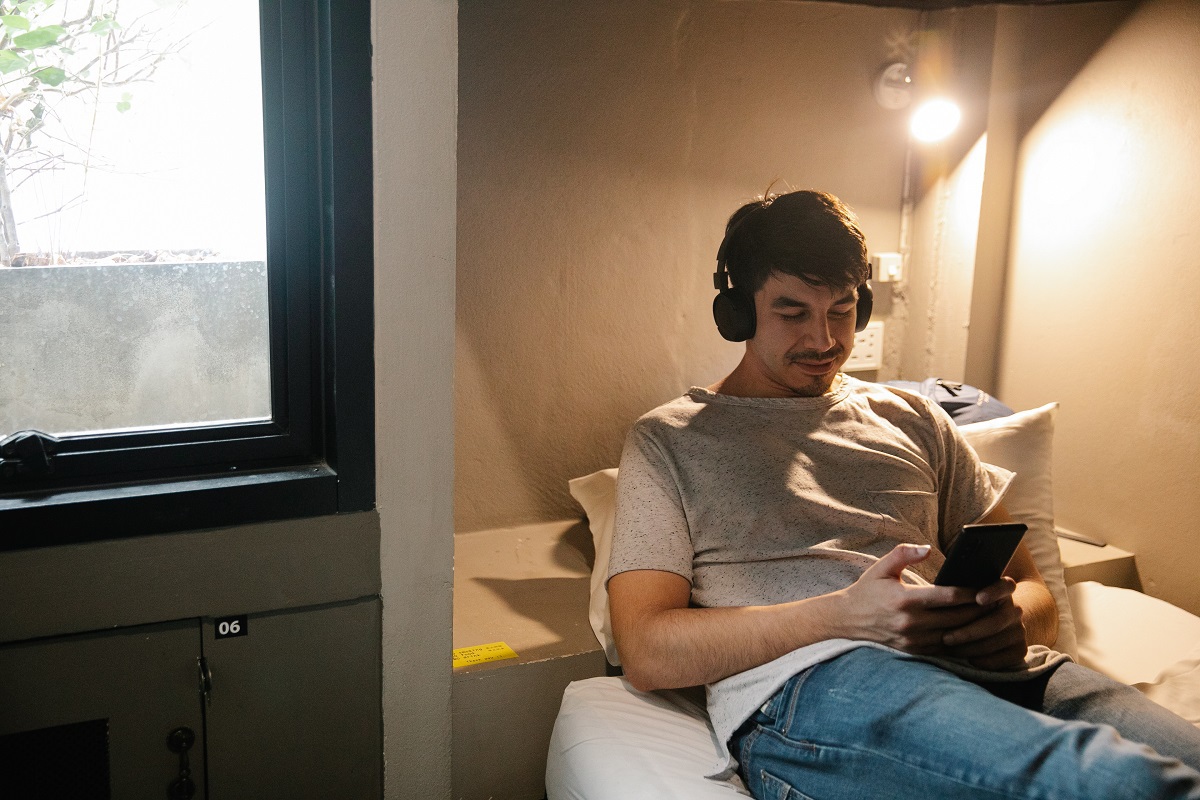 Headset: Aplicativos de filmes grátis Homem deitado em cama com fone de ouvido assistindo em Aplicativos de filmes grátis