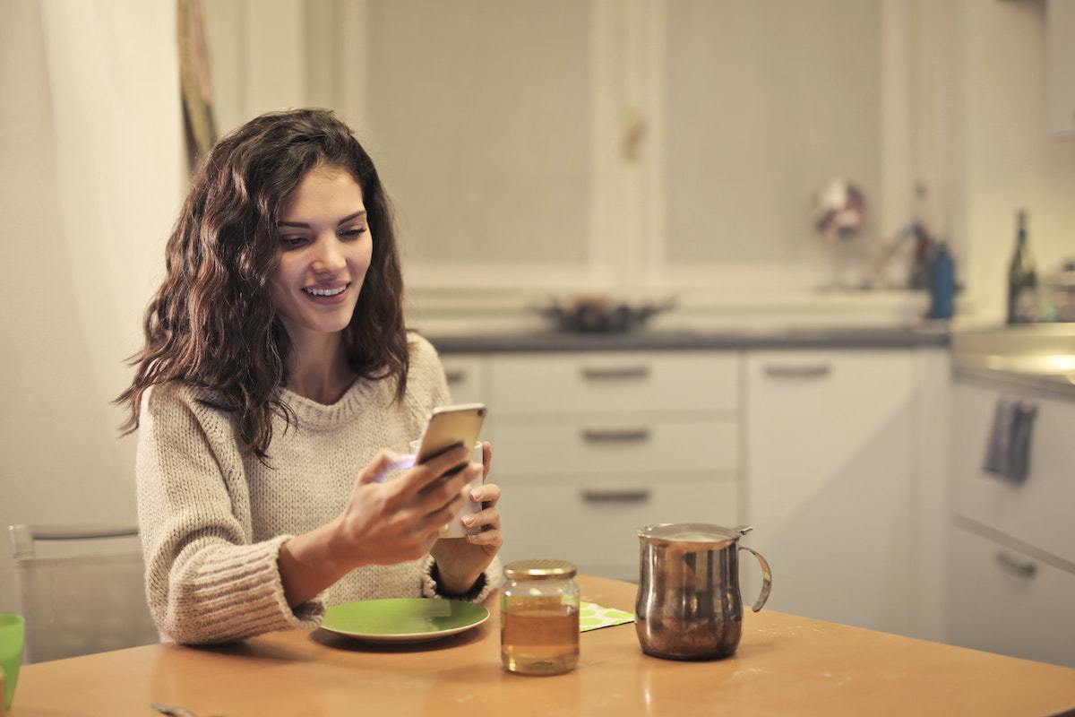 Casa: Apps para aprender inglês Mulher em casa com celular usando Apps para aprender inglês