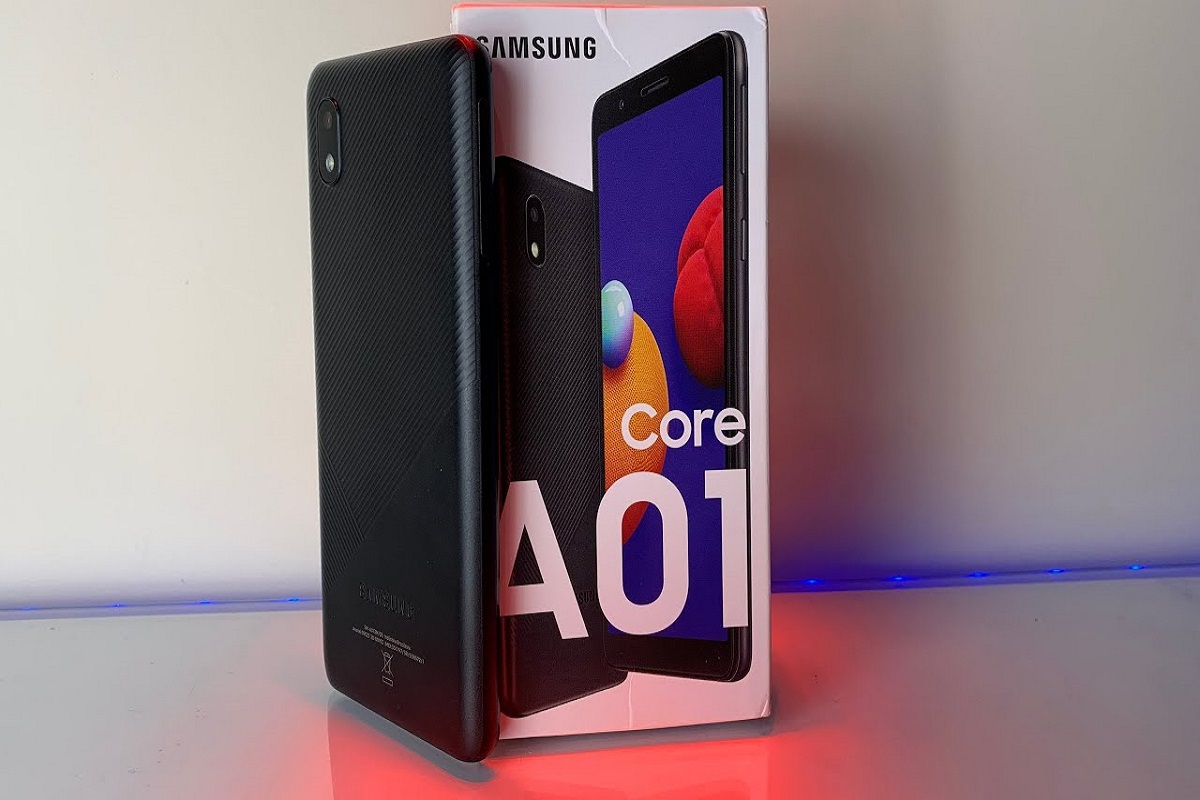 Galaxy A01 Core preto de pé ao lado de sua caixa sobre mesa com LED na cor magenta abaixo do mesmo