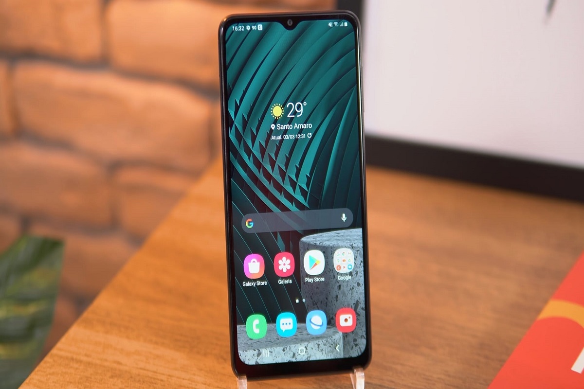 Galaxy A12 apoiado em suporte sobre mesa de madeira