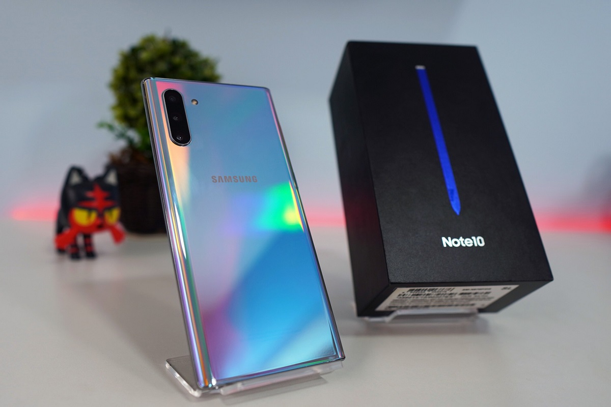Galaxy Note 10 azul mostrando seu verso ao lado de caixa do produto sobre mesa branca