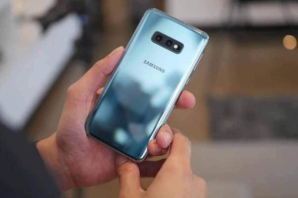 Galaxy S10e em tom cinza azulado com efeito espelhado na pintura segurado por usuário, que observa as costas do aparelho