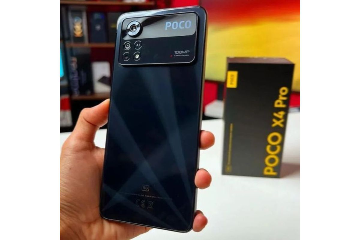 Usuário: Poco X4 Pro Poco X4 Pro na mão de usuário e com sua caixa ao fundo em desfoco sobre mesa