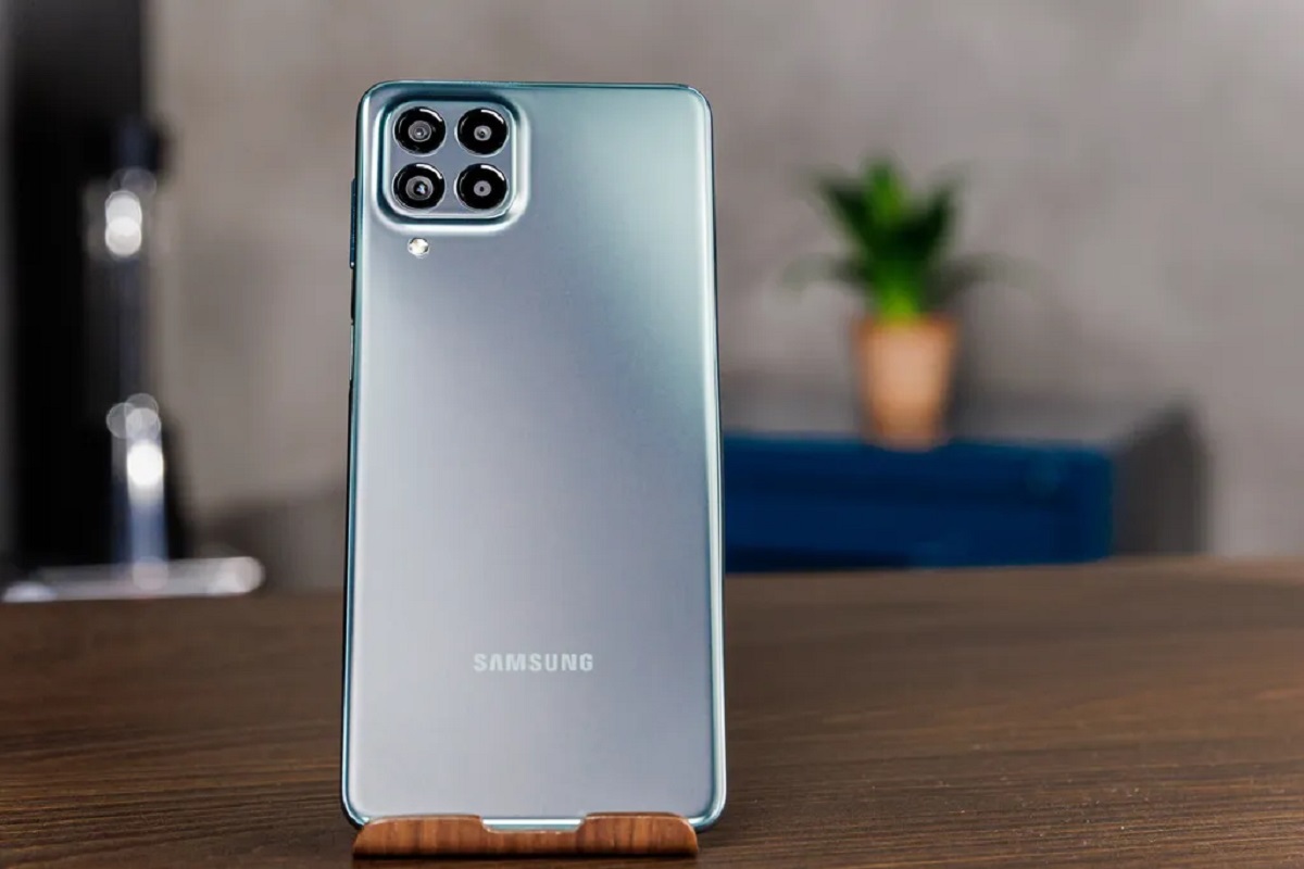 Samsung Galaxy M53 azul cinza azulado sobre mesa e suporte mostrando seus detalhes