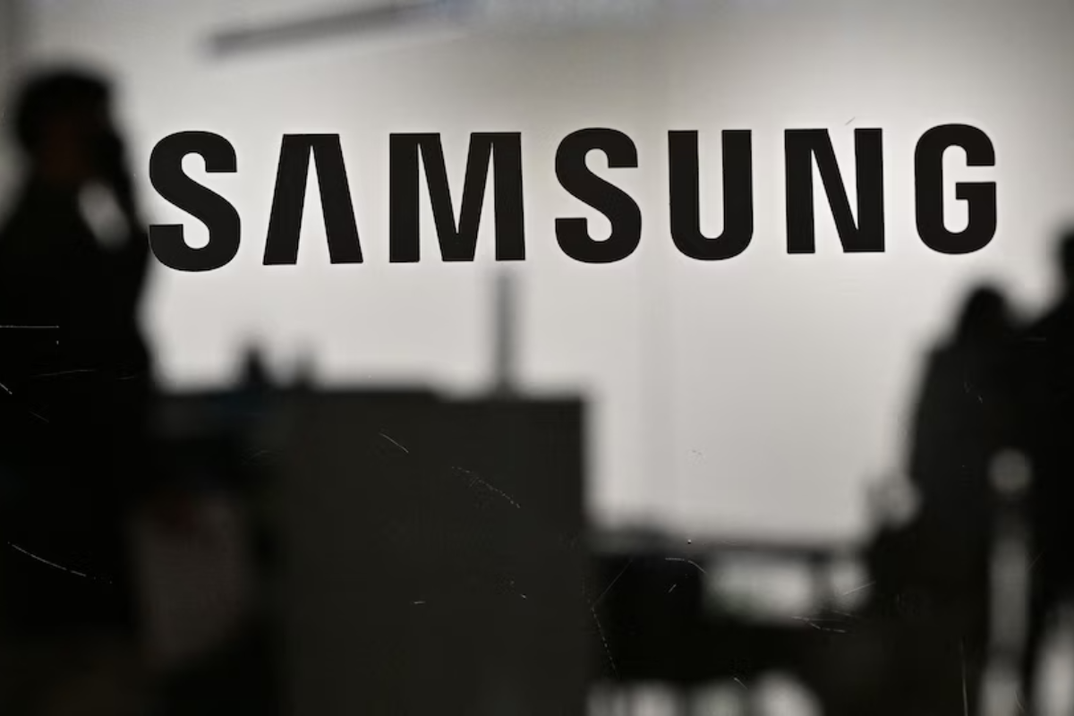 Nome e logomarca Samsung colados em vidro com objetos ao fundo em desfoco