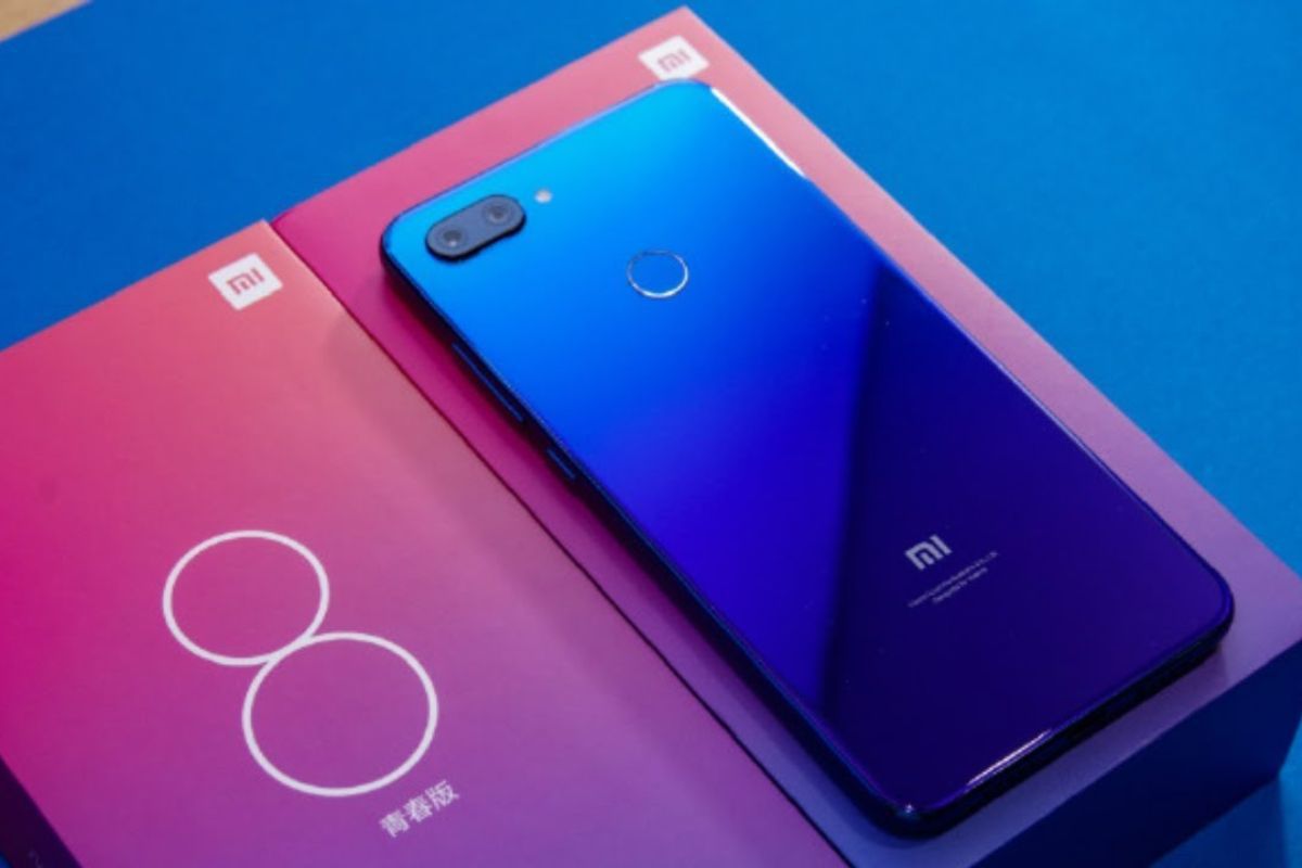 Xiaomi Mi 8 Lite sobre sua caixa em cima de superfície azul, mesma cor do aparelho, com as costas viradas para cima