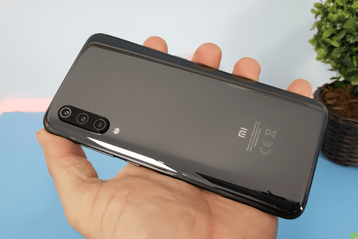 Usuário: Xiaomi Mi 9 Usuário segurando Xiaomi Mi 9 mostrando seus detalhes do verso