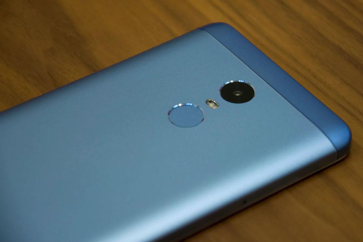 Câmera: Xiaomi Redmi Note 4X Xiaomi Redmi Note 4X azul sobre mesa de madeira com costas para cima mostrando sua câmera traseira e sensor para leitura de impressão digital