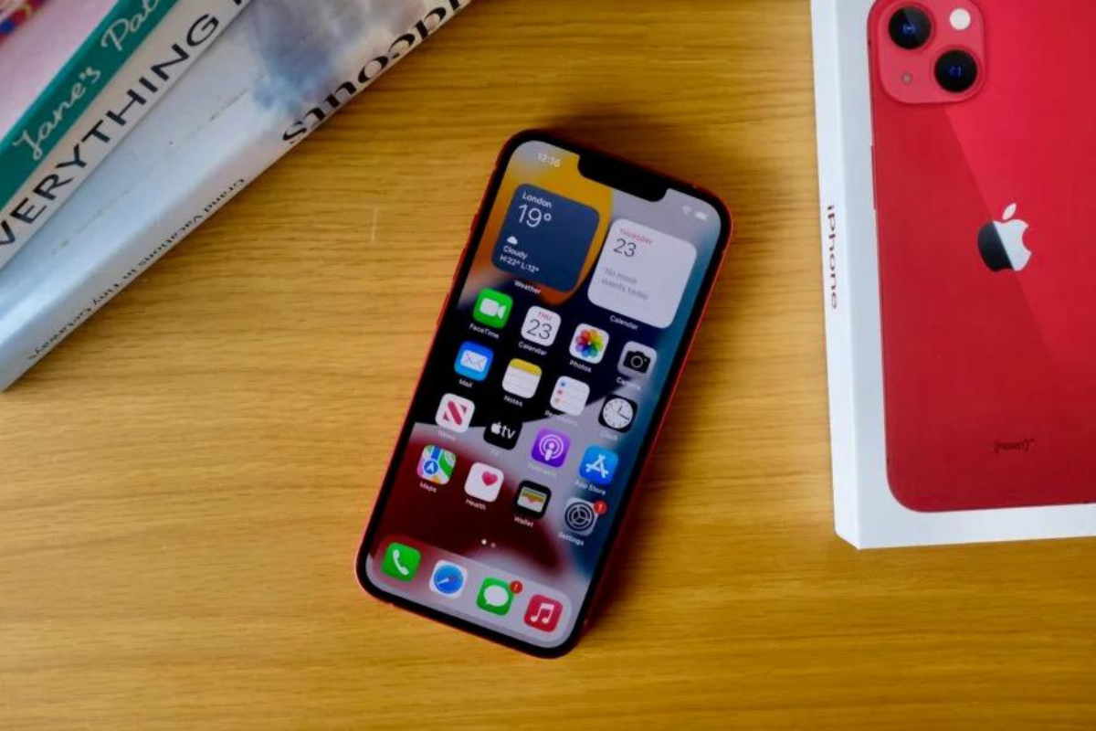 iPhone 13 sobre mesa de madeira e ao lado de sua caixa